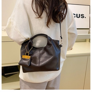 Détail d'un sac cabas marron café en similicuir avec un mini pendentif assorti