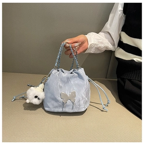 Close-up of light blue drawstring bucket bag with silver butterfly and plush charm