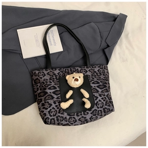 Detail of leopard print canvas tote bag featuring 3D plush bear and black pocket