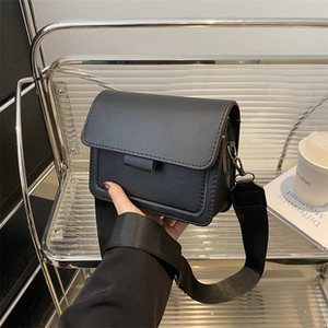 Detail der minimalistischen schwarzen Umhängetasche mit verstellbarem Riemen und Glattleder