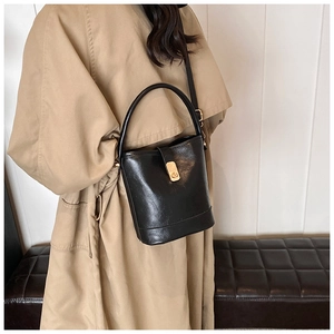 Detailed close-up of a black textured bucket bag with a stylish gold metal clasp closure
