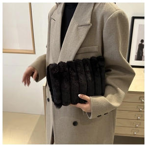 Détail d'une pochette en fausse fourrure noire avec texture rayée verticale et toucher doux