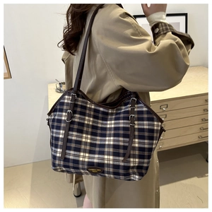 Detail of blue and beige plaid canvas tote with brown leather strap and brand logo