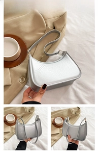 Detail view of silver crescent underarm bag showing wrinkled texture and metal buckle