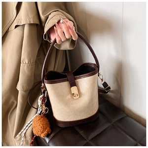 Detail of vintage bucket bag with contrast leather trim, metal lock and teddy charm