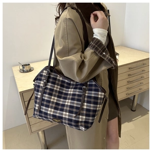 Detail of vintage plaid tote bag with brown leather trim and metallic brand logo