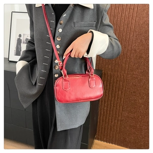 Detail of red glossy Boston bag with gold hardware and shoulder strap on model