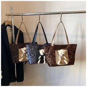 Detail of leopard print tote bags featuring a 3D plush bear charm in the front pocket