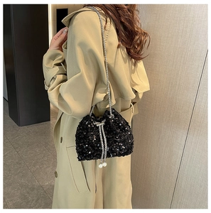 Detailed shot of black sequin bucket bag featuring silver chain drawstring and pearl accents