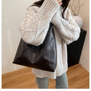 Minimalist black leather tote bag shown with a white cable knit sweater for daily styling