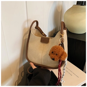 Detail of minimalist cream Hobo bag with brown trim and cute teddy bear keychain
