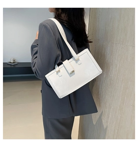 Side view of white minimalist square shoulder bag with gold buckle on a model in a blazer