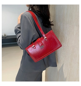 Detail of red patent leather baguette bag with golden hardware and adjustable straps
