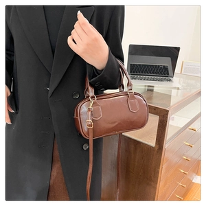 Brown leather Boston bag detail showing hand-carry style in a modern office setting