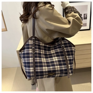 Detail of adjustable leather shoulder strap and plaid canvas texture on large tote bag