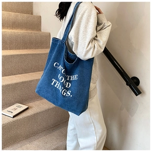 Blue denim tote bag detail featuring white letter print and comfortable wide strap