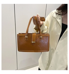 Close-up of a brown rectangle handbag with glossy finish and metal buckle detail