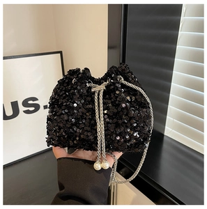 Close-up of black sequined bucket bag with pearl drawstring and silver chain strap