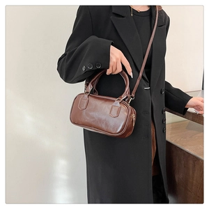Detail view of a vintage brown leather bowling bag with round handles and metal zippers