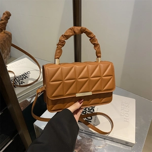 Brown quilted leather handbag with ruched handle and gold metal buckle on fashion books
