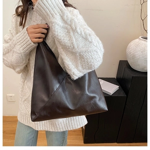 Close-up of vintage dark brown faux leather tote bag with unique geometric folding design