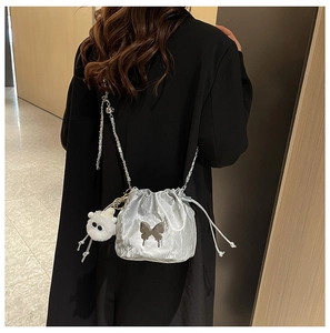 Silver metallic bucket bag with butterfly detail and plush charm on black coat