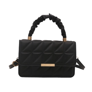 Minimalist black quilted handbag with cloud-like handle and golden hardware on white background