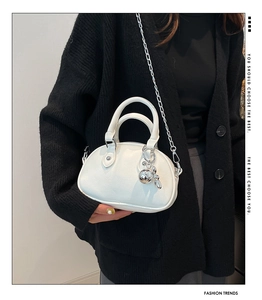 Détail du sac bandoulière blanc à texture litchi avec chaîne argentée et pendentif