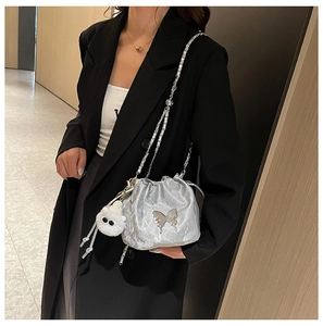 Detail of silver metallic drawstring bucket bag with butterfly ornament and plush charm