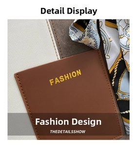 Detail of brown lychee leather tote bag featuring a yellow embossed Fashion logo and stitching