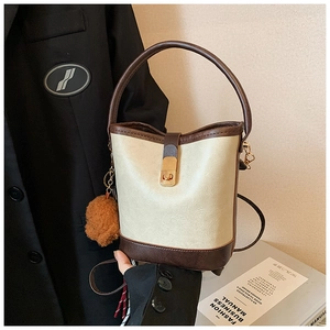 Detail of vintage bucket bag with beige textured leather and brown plush charm