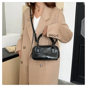Détail du sac à main en cuir verni noir avec boucles dorées et bandoulière réglable