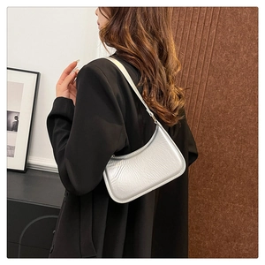 Detail of silver metallic crescent bag with pleated texture on black blazer sleeve