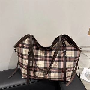 Retro plaid canvas tote bag in brown and pink with leather straps on a black seat
