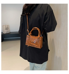 Detail of dark brown PU leather crossbody bag with heart cutout and bow decoration