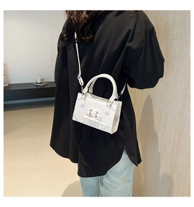 Detail of white mini crossbody bag featuring heart cutout design and matching ribbon bow