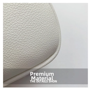 Détail de la texture en cuir blanc grainé et coutures précises sur un sac bandoulière