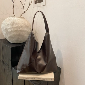 Minimalist large brown tote bag in glossy oil wax leather shown on decorative books