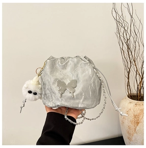 Detail of silver pleated bucket bag with butterfly emblem, metal chain and fur pompom