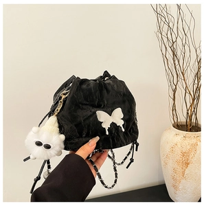 Close-up of black drawstring bucket bag with butterfly patch and plush charm detail