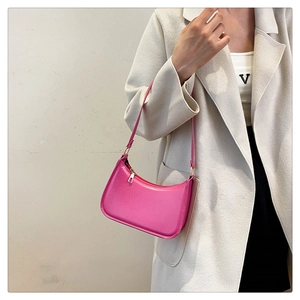 Close-up of bright pink faux leather baguette bag showing texture and silver metal zipper