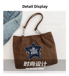 Detail view of brown suede tote bag with blue denim star patch and metal chain strap