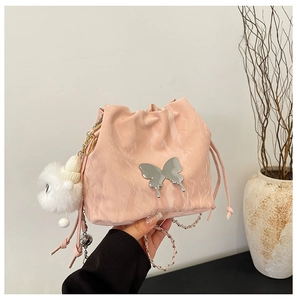 Detailed shot of pink textured bucket bag featuring silver butterfly and monster plush charm