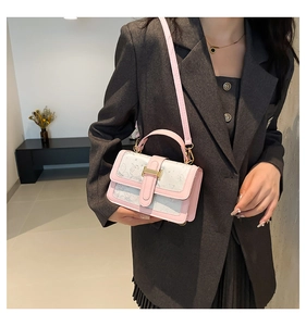 Fashionable pink butterfly shoulder bag worn with a gray suit in a modern indoor setting