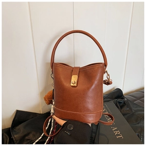 Detail of vintage brown textured bucket bag with golden twist lock and plush charm