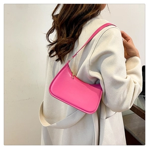 Close-up of vibrant pink half-moon underarm bag styled with a cream-colored coat