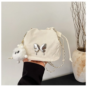 Detail of white pleated bucket bag with silver butterfly charm and plush doll keychain