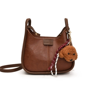 Brown vintage faux leather tote with plush dog charm and adjustable shoulder strap