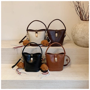 Detail view of four textured bucket bags in various colors with plush bear charms