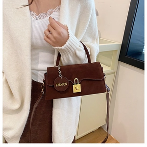 Dettaglio della borsa in pelle scamosciata marrone con fibbia dorata e ciondolo